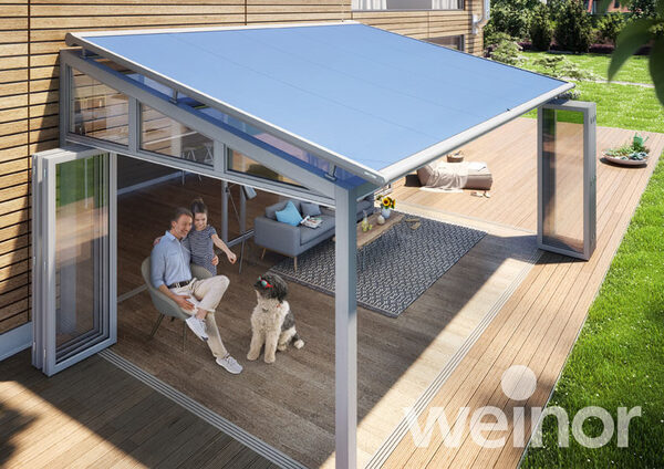 Moderne Terrassenüberdachung mit Glasdach, Sitzbereich, Familie und Hund im Garten.