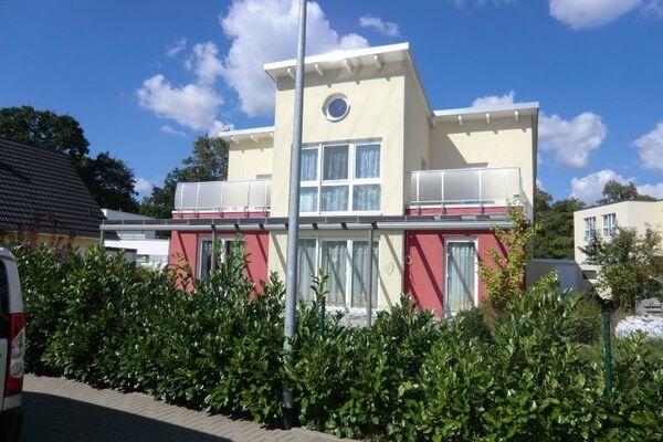 Modernes Einfamilienhaus mit Flachdach, Balkon und großen Fenstern in ruhiger Wohngegend.