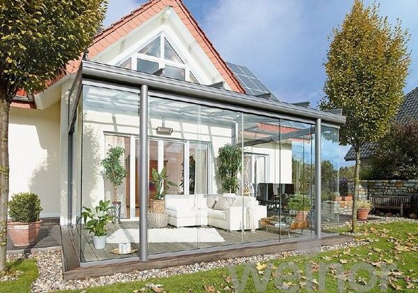 Moderner Wintergarten mit Glasüberdachung und gemütlicher Sitzecke am Einfamilienhaus.