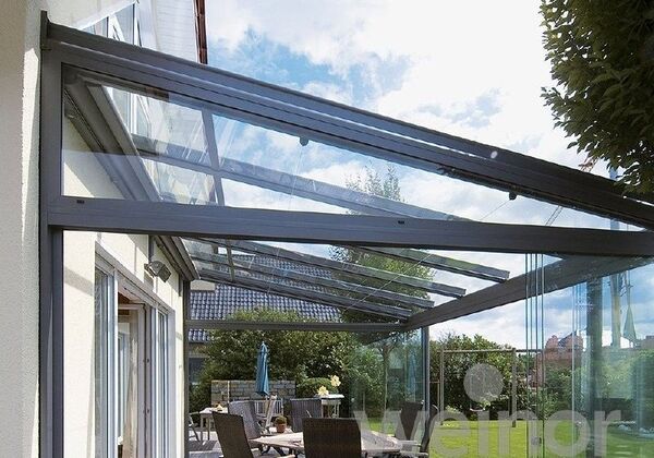 Moderne Terrassenüberdachung aus Glas mit Aluminiumrahmen an einem Einfamilienhaus.