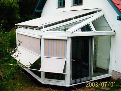 Wintergarten mit Glasdach und Markisen an Einfamilienhaus für optimalen Sonnenschutz.