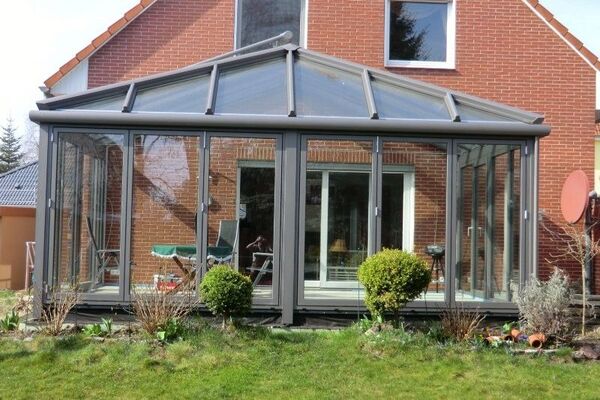 Moderner Wintergarten mit Glasdach und Schiebetüren an einem Einfamilienhaus im Garten.