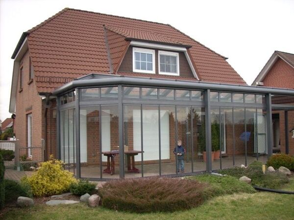 Wintergarten aus Glas und Aluminium an Einfamilienhaus mit Garten und moderner Verglasung.