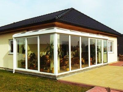 Moderner Wintergarten mit großen Glasfronten an Einfamilienhaus im Gartenbereich.